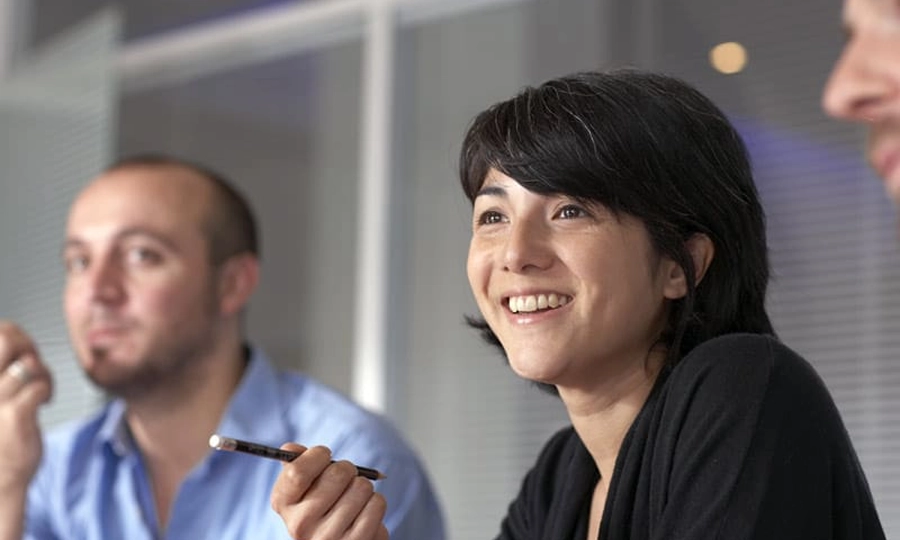 Twee lachende collega’s in een vergadering binnen de financiële sector.