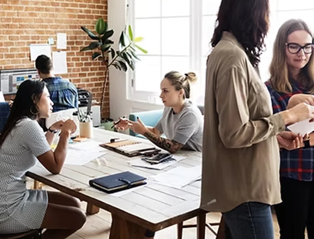 Mensen werken en overleggen samen in een moderne kantoorruimte met een informele sfeer.