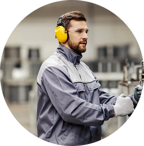 Trabajador industrial operando maquinaria con equipo de protección en una planta de producción.