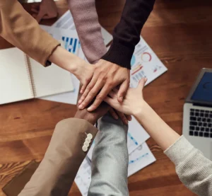 Verschillende handen op elkaar gestapeld als symbool voor samenwerking en teamspirit op de werkplek.