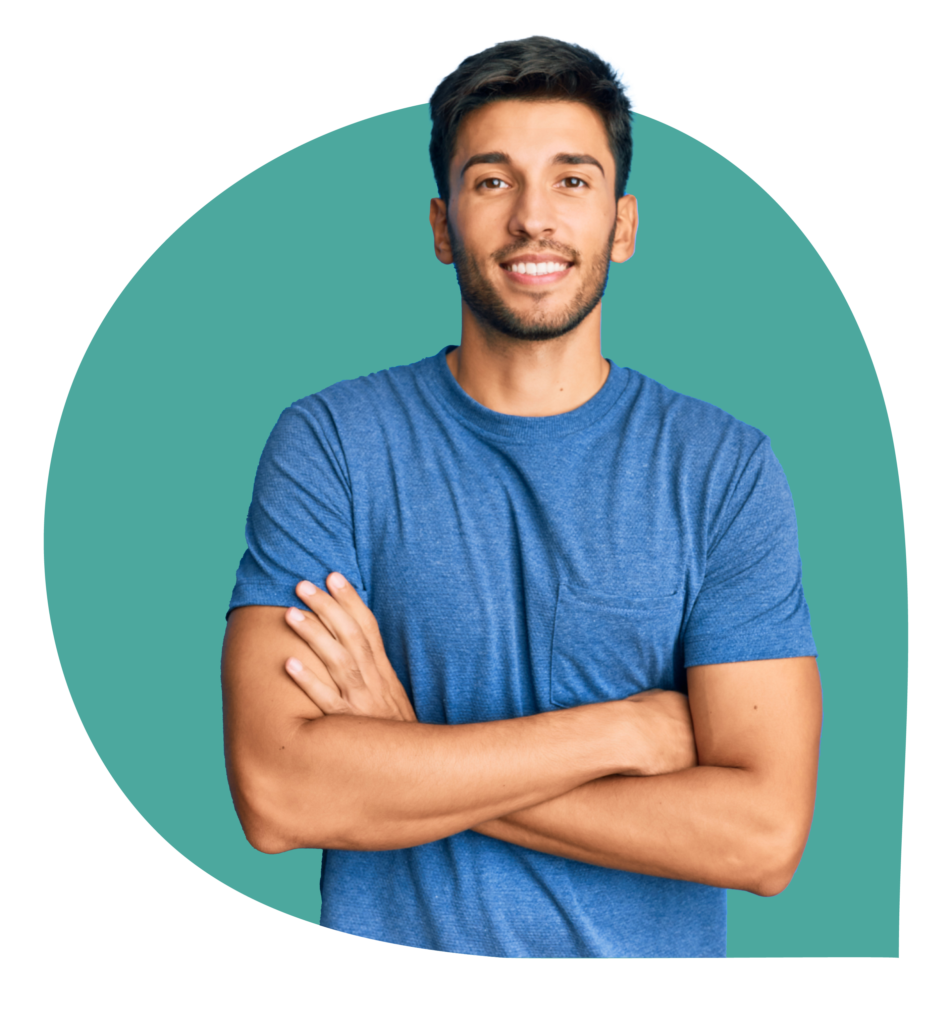 Jonge man met donker haar in een blauw T-shirt die glimlacht en met gekruiste armen voor een turquoise achtergrond staat.