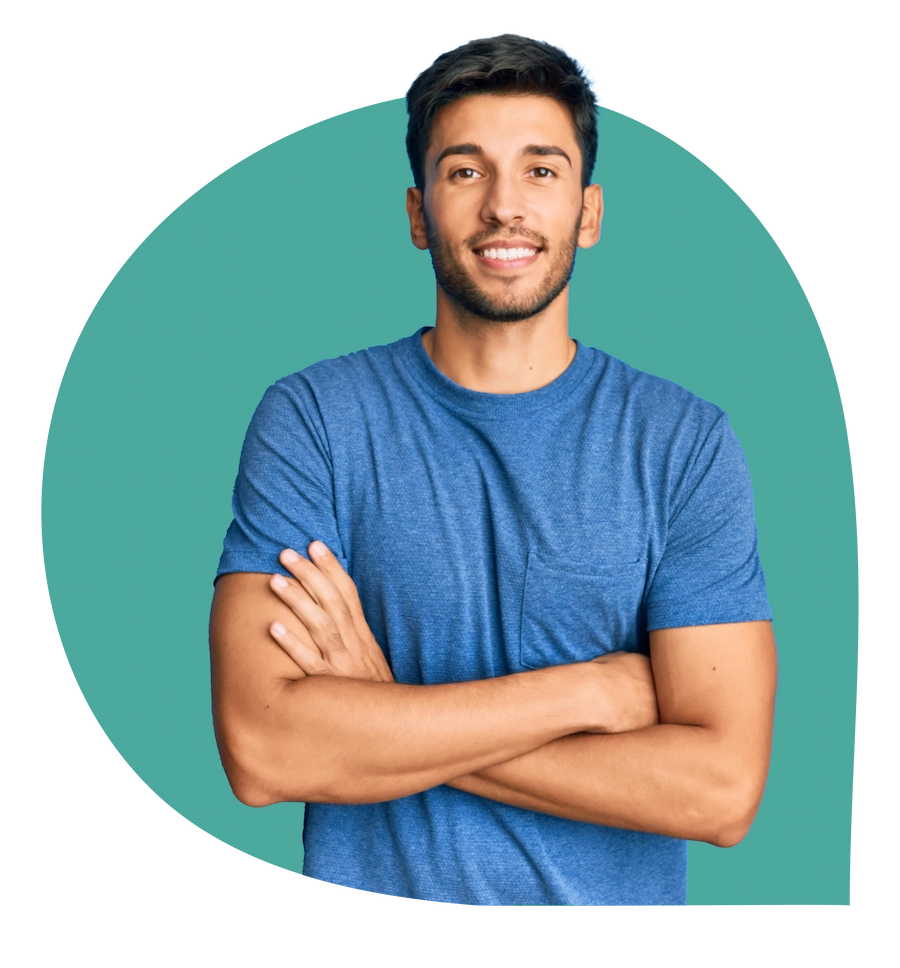 Jonge man met donker haar in een blauw T-shirt kijkt glimlachend naar de camera met armen over elkaar.