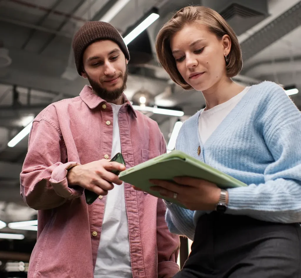 Twee personen bespreken werk terwijl ze samen naar een tablet kijken.