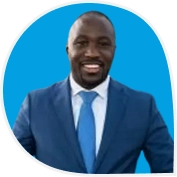 Portret van Jonathan in een blauw pak met stropdas, lachend voor een blauwe achtergrond.